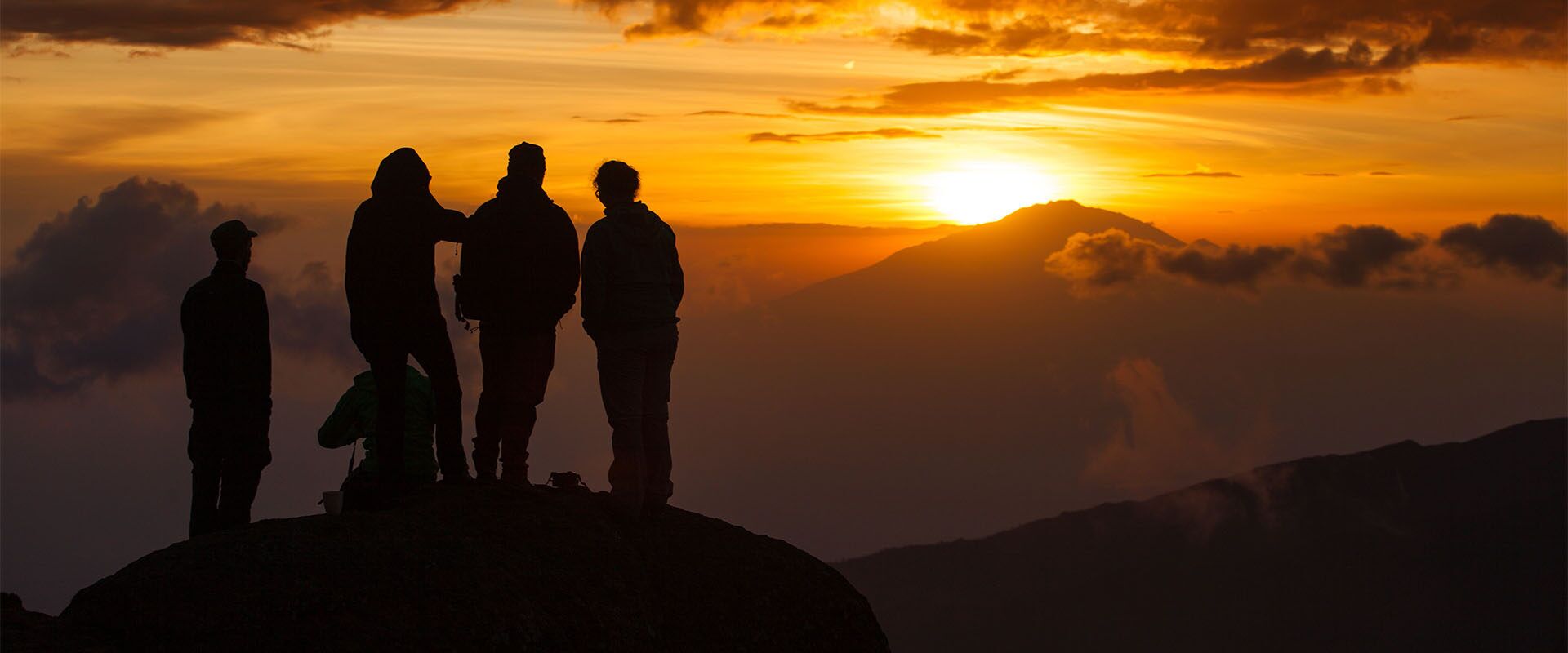 A group of hikers standing on Mount Kilimanjaro during sunset
