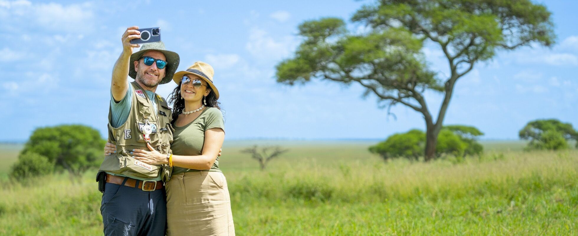 A couple in Tanzania taking a selfie in front of an acacia tree