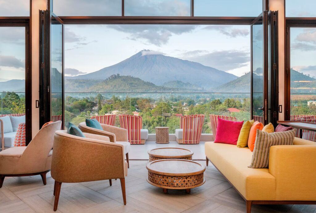 Gran Melia lounge with bright armchairs, a yellow couch, open doors to the terrace and Mount Meru in the background