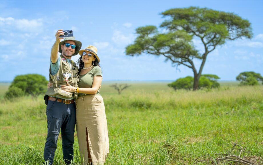 A couple in Tanzania taking a selfie in front of an acacia tree