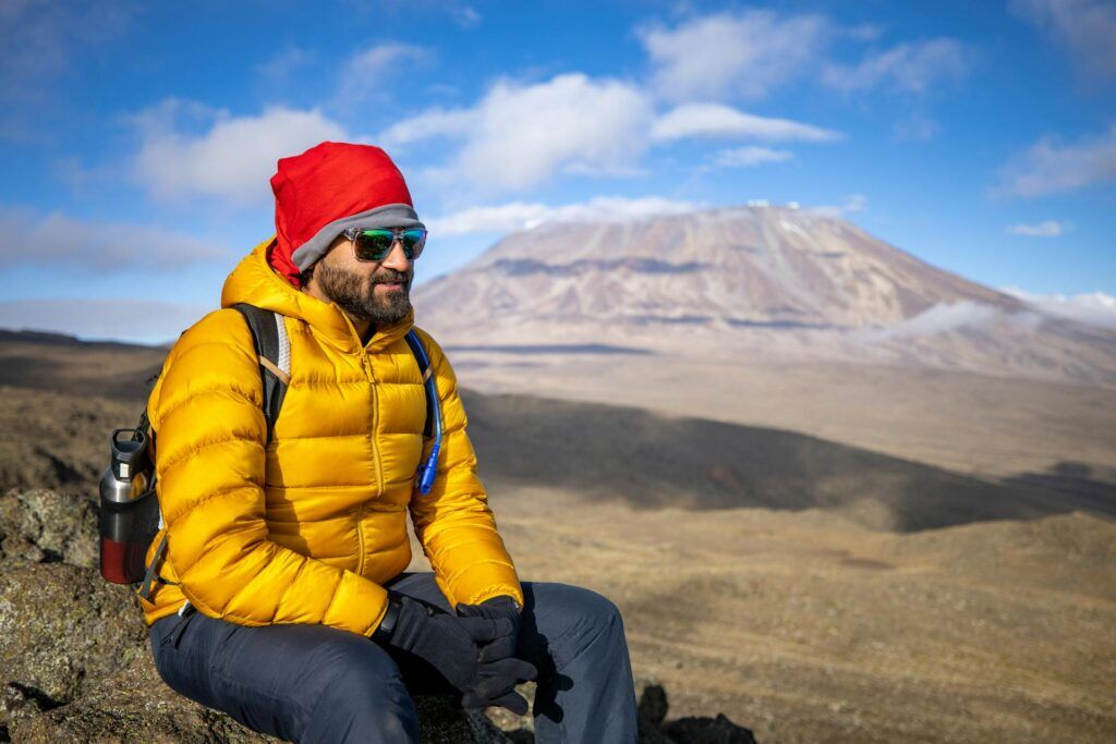 Man sitting on a rock while climbing Kilimanjaro