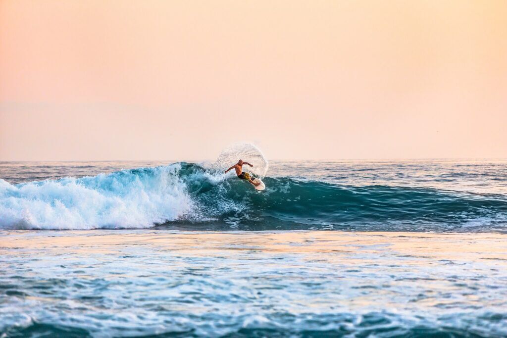 Man surfing on a wave during sunset