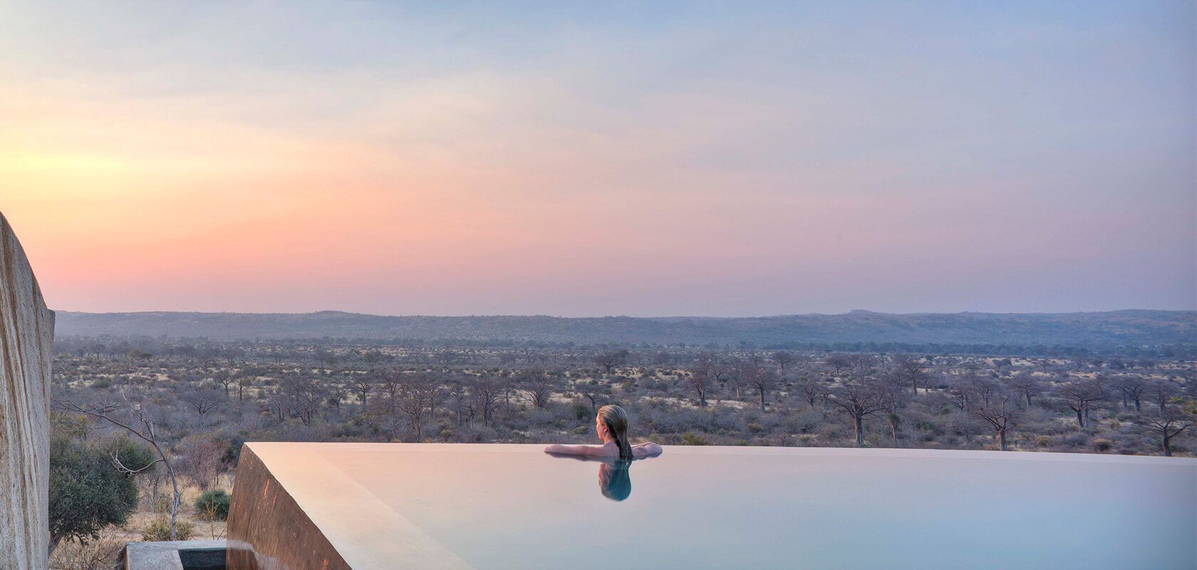 Woman in an infinity pool watching the sunset