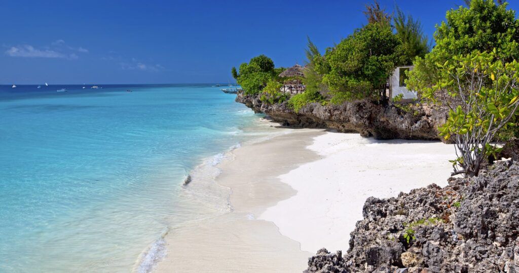 blauwe zee met strand en rotje op zanzibar