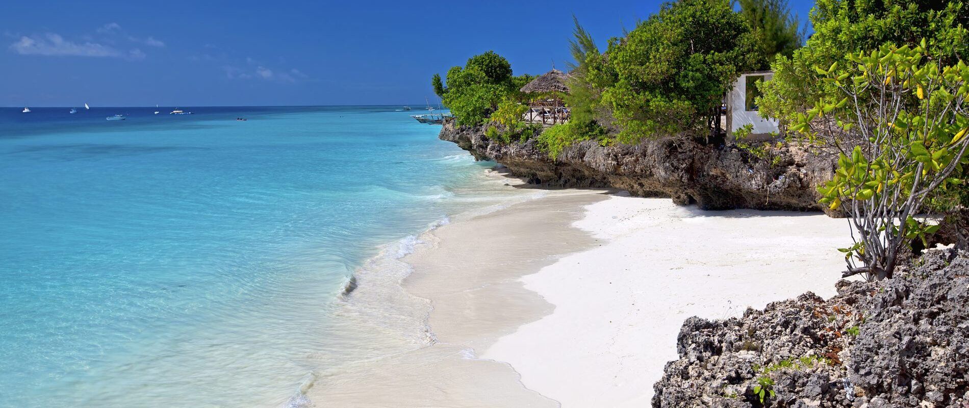 blauwe zee met strand en rotje op zanzibar