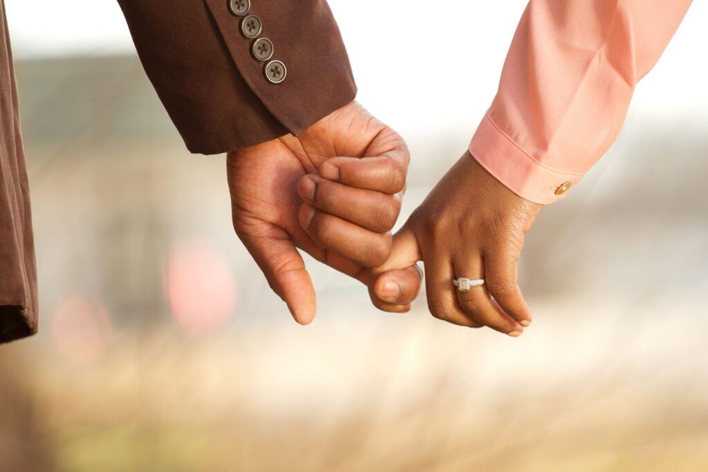 Two hands holding each other, one has a ring