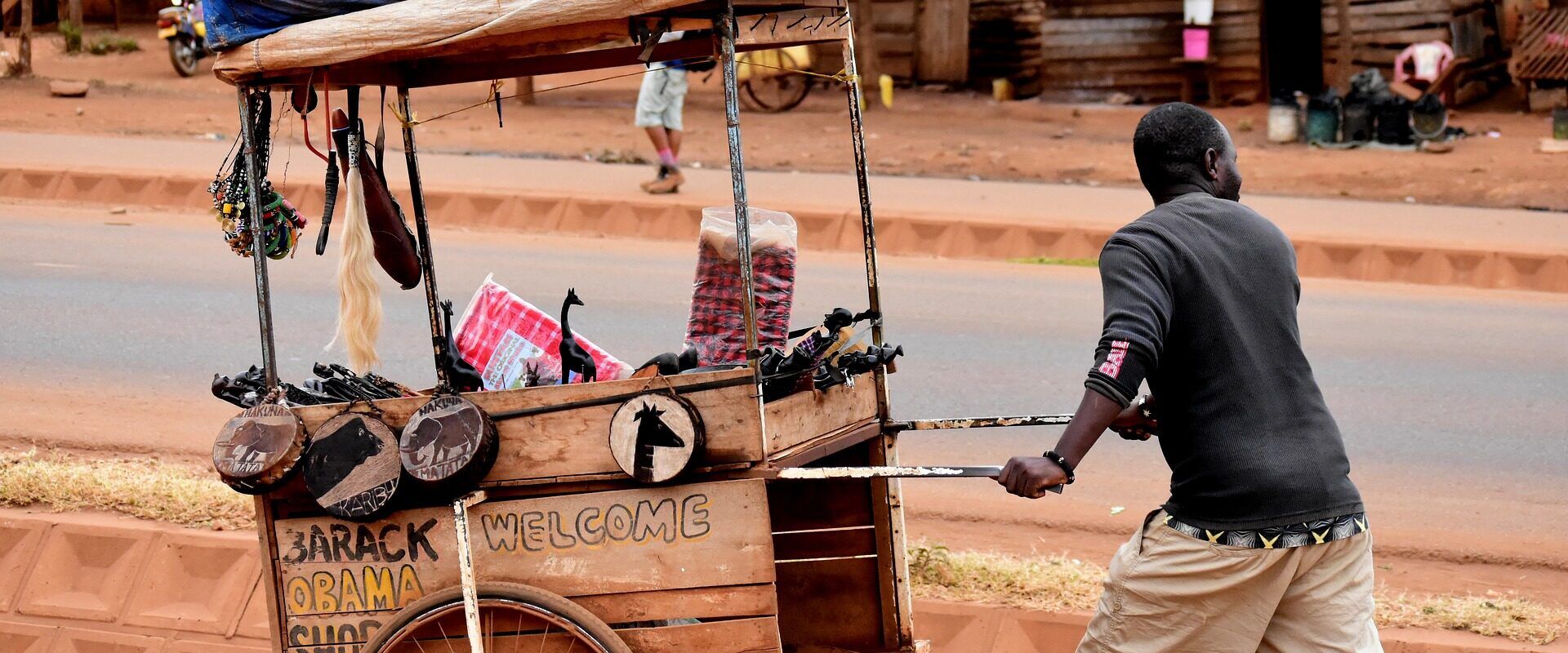 Man pushing a cart with African sculptures